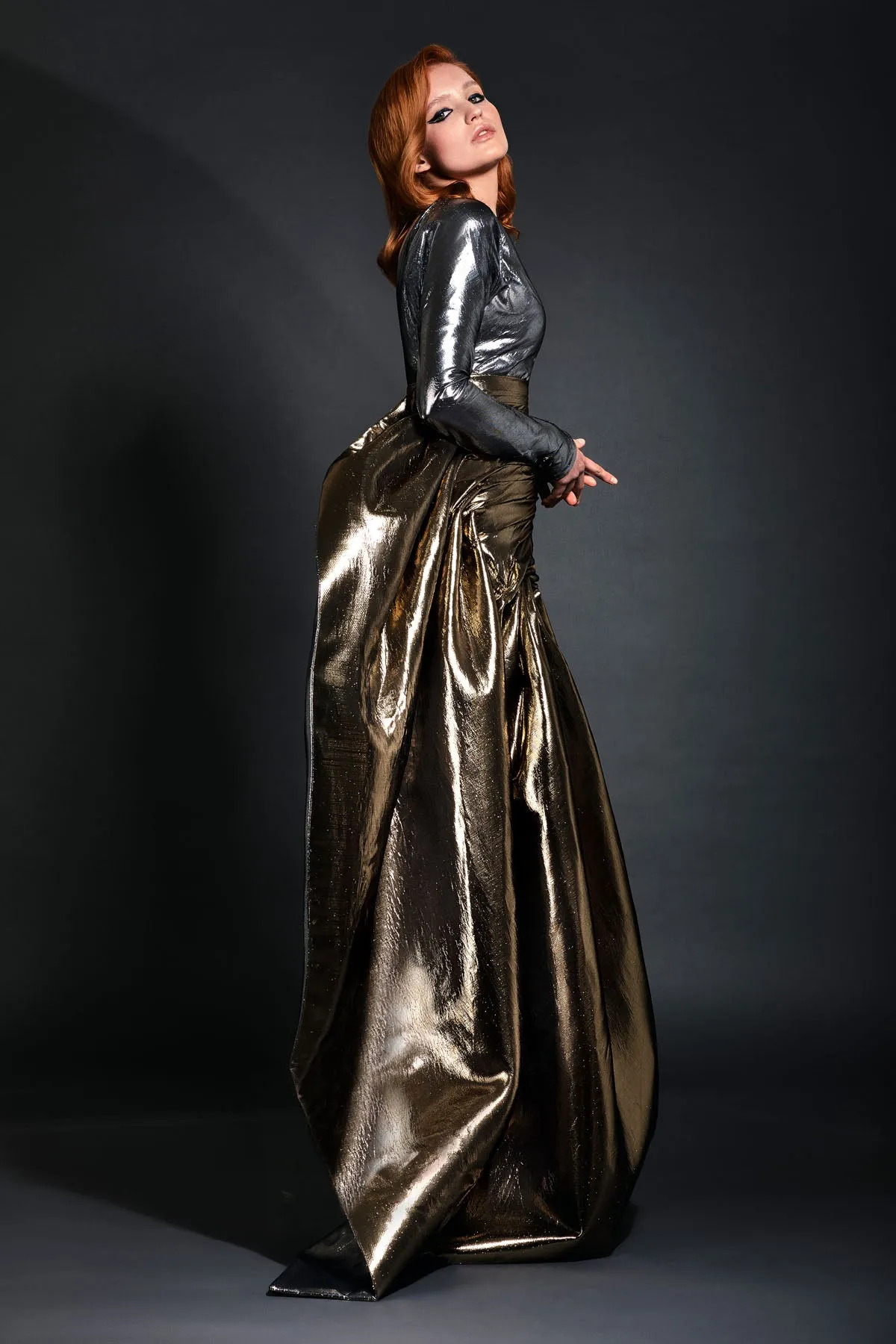 Gunmetal lamé one shoulder bustier accompanied by a pleated gold lamé skirt with floor length bustle