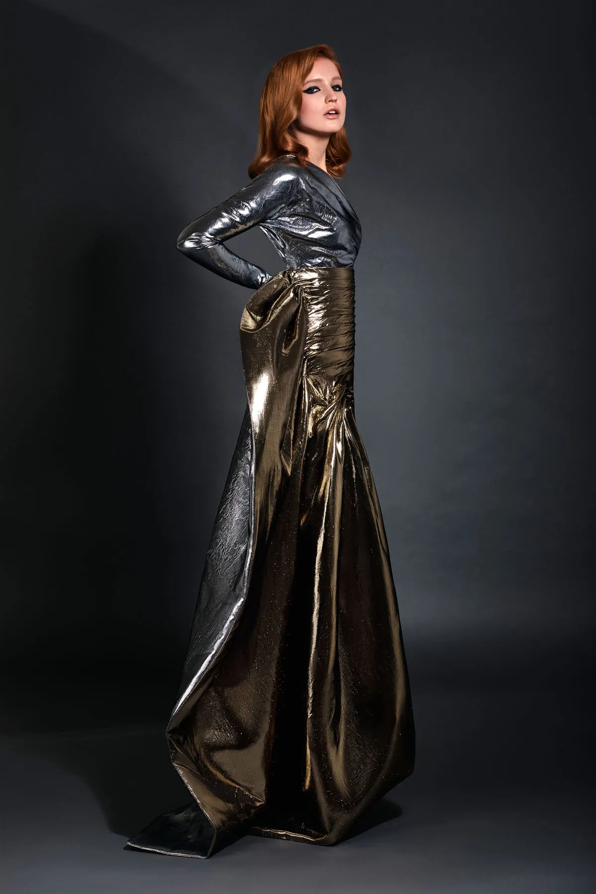 Gunmetal lamé one shoulder bustier accompanied by a pleated gold lamé skirt with floor length bustle